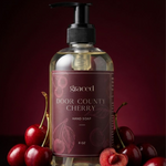 Bottle of Door County Cherry hand soap with cherries on a dark background