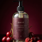 Bottle of Door County Cherry hand soap with cherries on a dark background