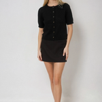 Woman wearing a black button-up shirt and black skirt on a white background