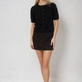 Woman wearing a black button-up shirt and black skirt on a white background