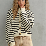 Woman wearing a black and white striped sweater with wooden buttons against a gray background