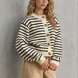 Woman wearing a black and white striped sweater against a gray wall