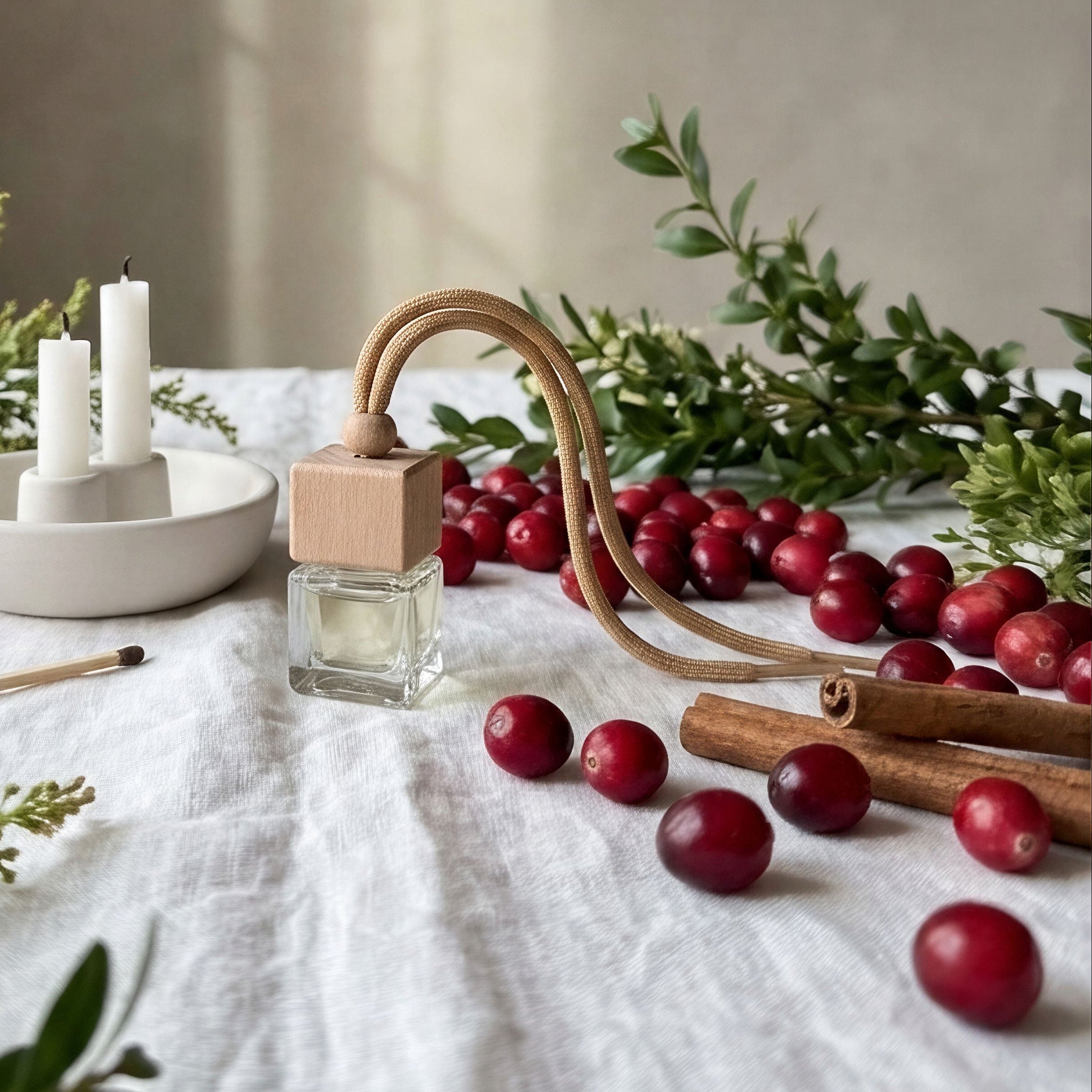 Table setting with candles, berries, and greenery on a neutral background