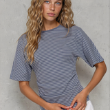 Woman wearing a blue and white striped shirt against a gray concrete wall