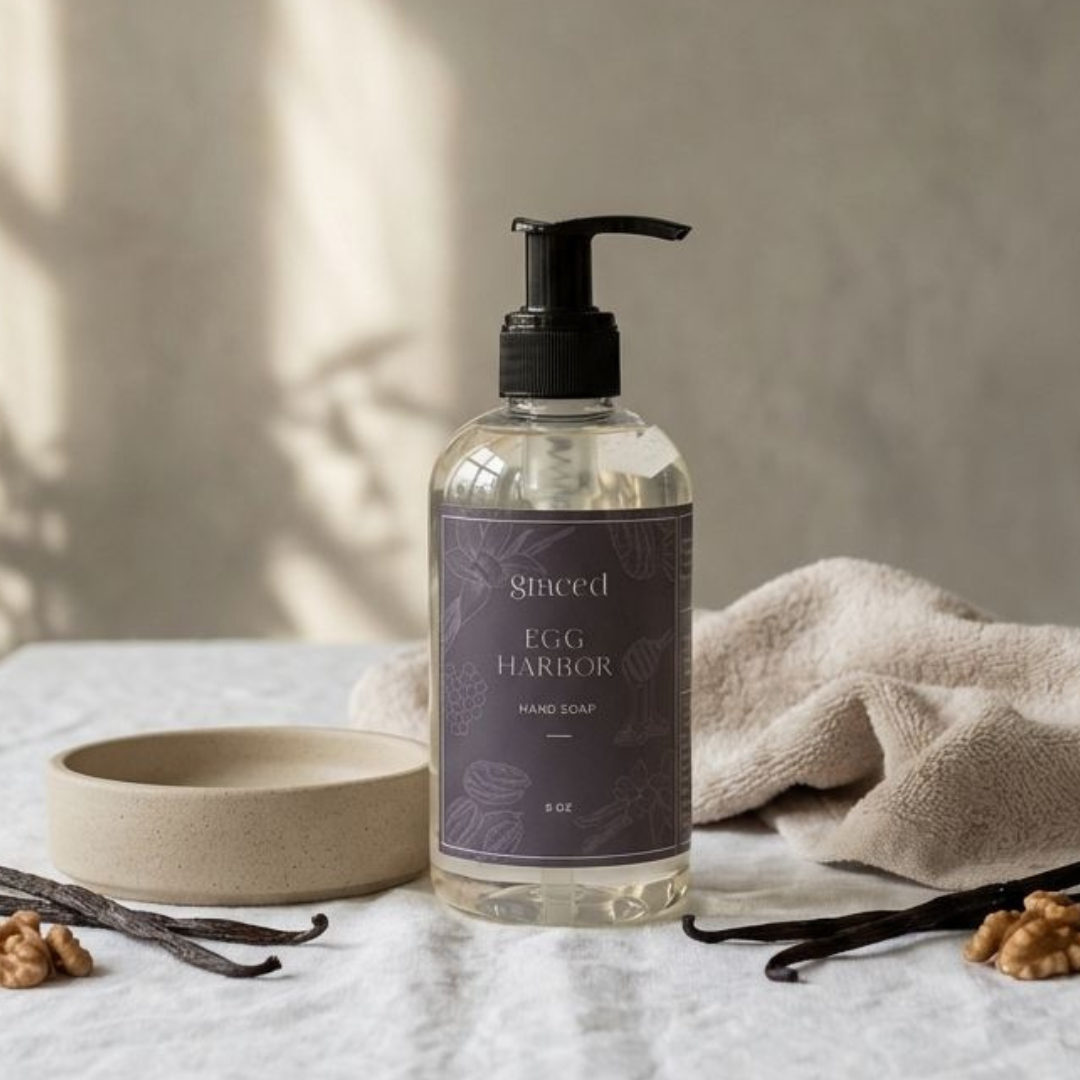 Hand soap bottle with a purple label on a textured surface with a towel and vanilla beans.