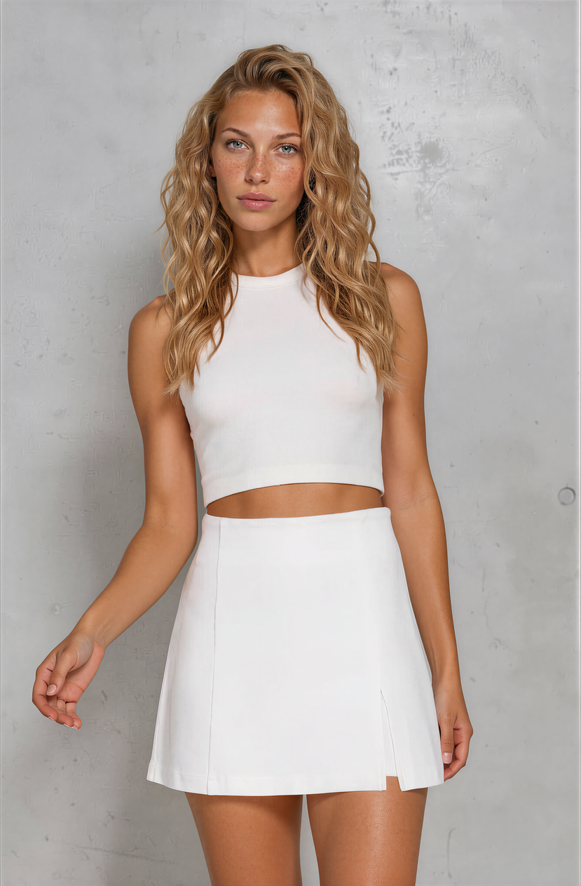Woman wearing a white sleeveless top and skirt against a gray background