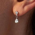 Silver teardrop earring worn on an ear