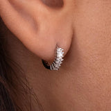 Silver hoop earring worn by a person with a neutral background