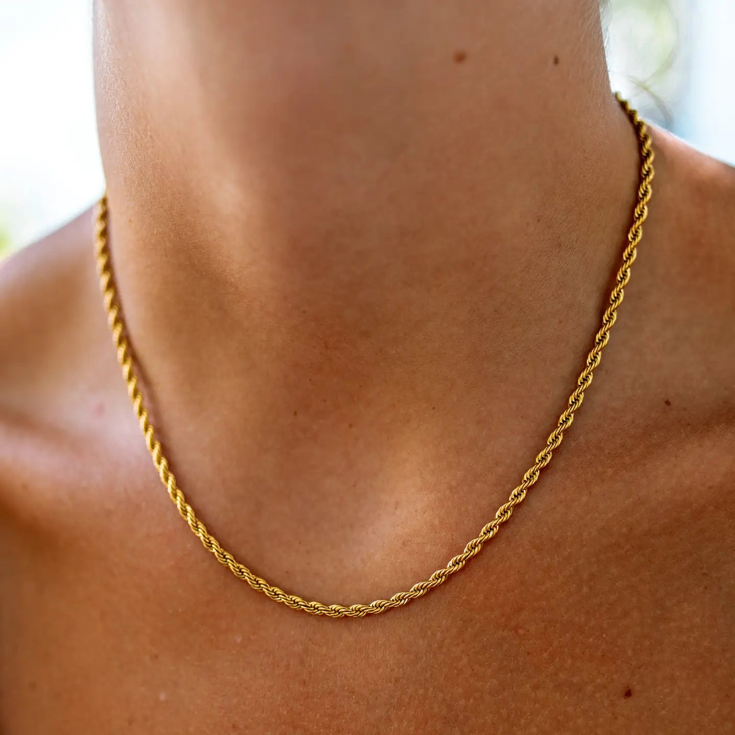 Gold chain necklace on a person's neck with a blurred background