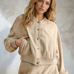 Woman wearing a beige cardigan over a dress against a textured wall background