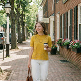 Woman walking down a street holding a coffee cup and a handbag