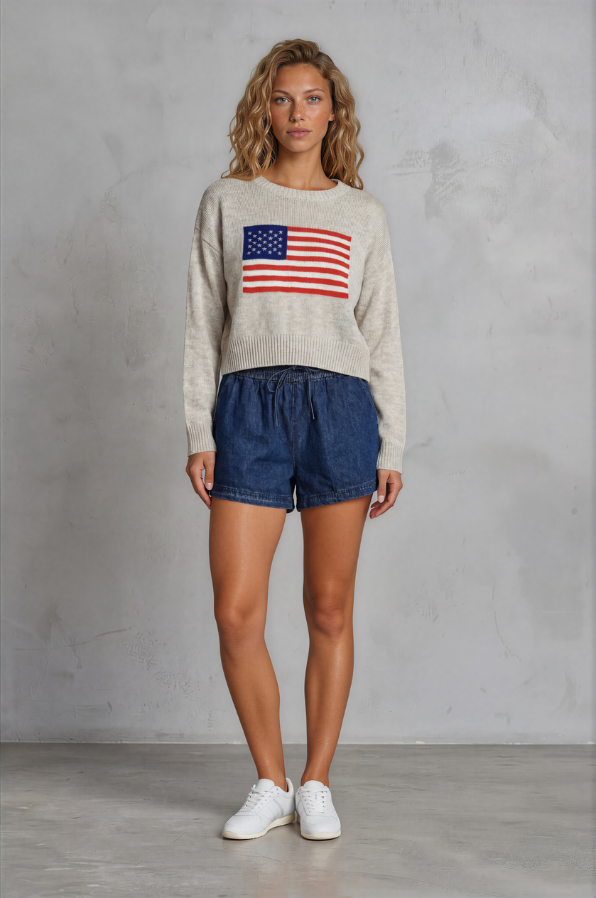 Woman wearing a sweater with an American flag design against a plain background