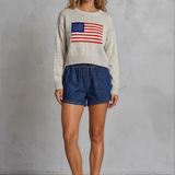 Woman wearing a sweater with an American flag design against a plain background