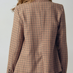 Person wearing a plaid blazer and beige pants against a white background