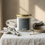 Candle labeled 'Sweet Lake Life' on a table with folded towels and a plate.