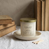 Candle labeled 'Library' on a plate with books in the background