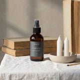 Bottle of 'Library' room spray on a table with books and candles
