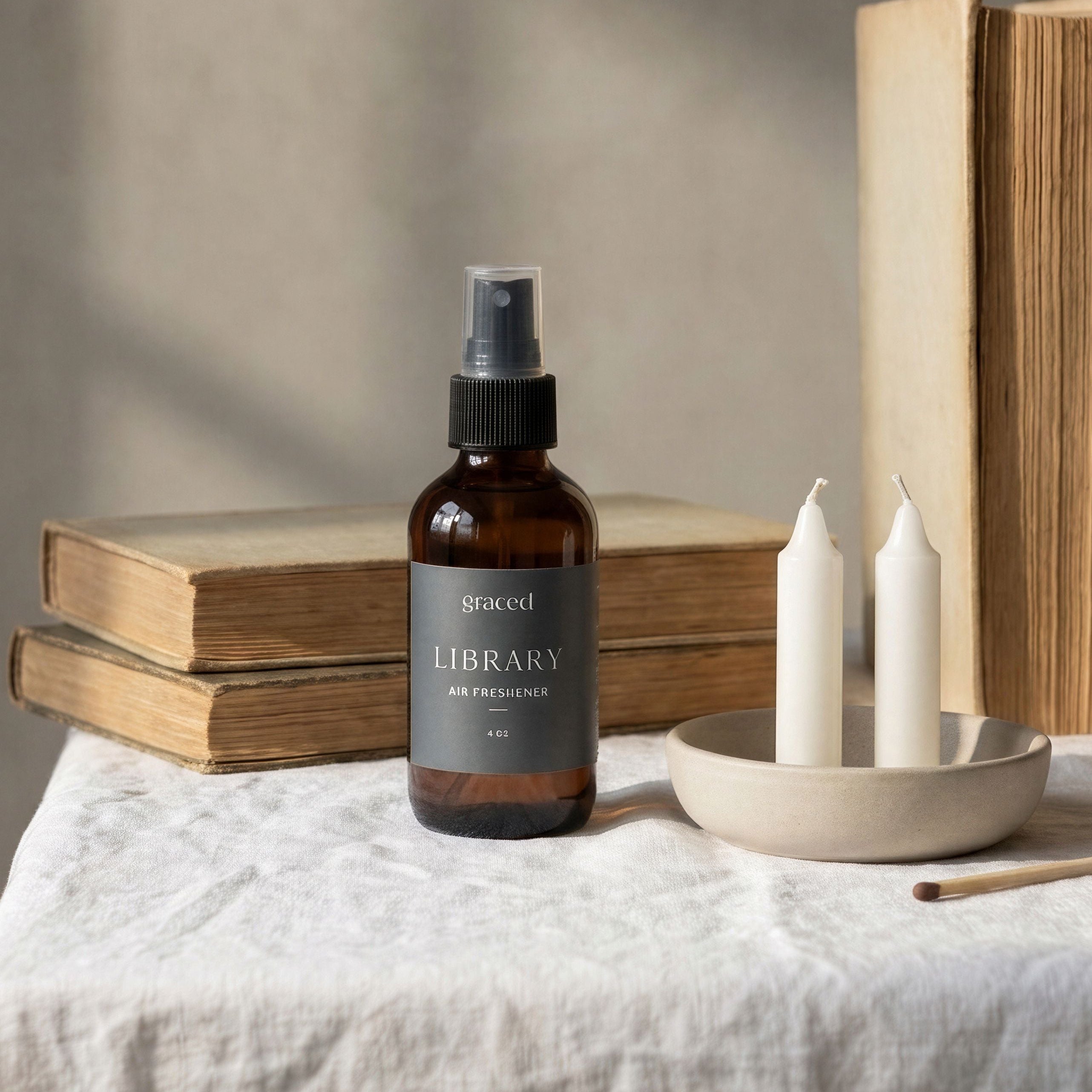 Bottle of 'Library' room spray on a table with books and candles