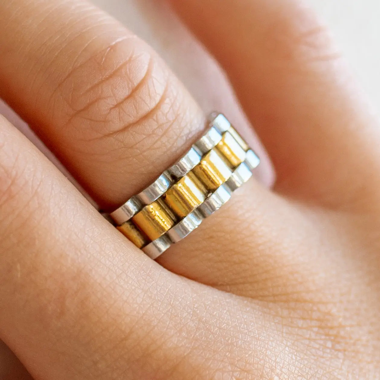 Close-up of a hand wearing a silver and gold ring.