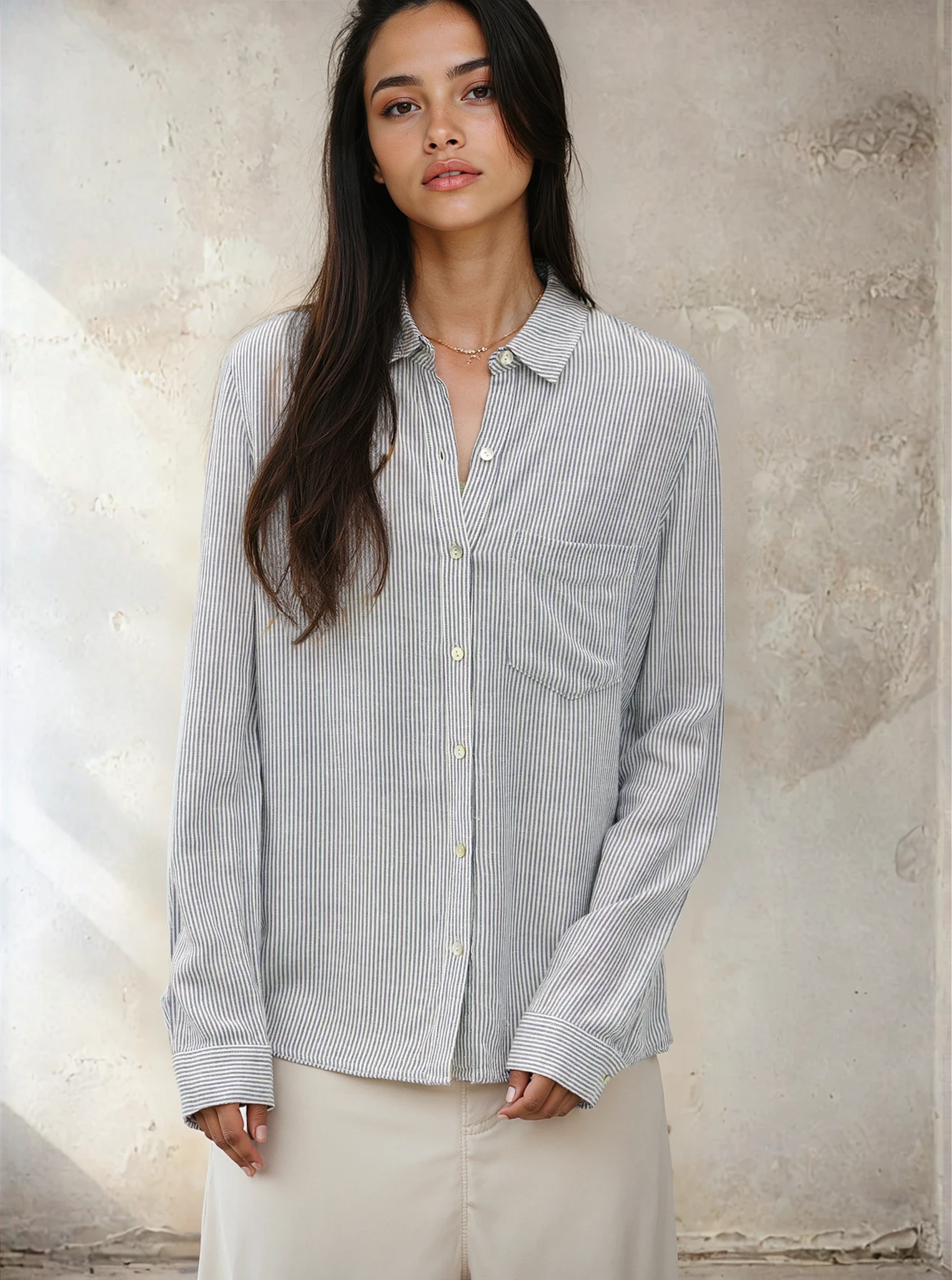 Woman wearing a striped shirt against a textured wall.