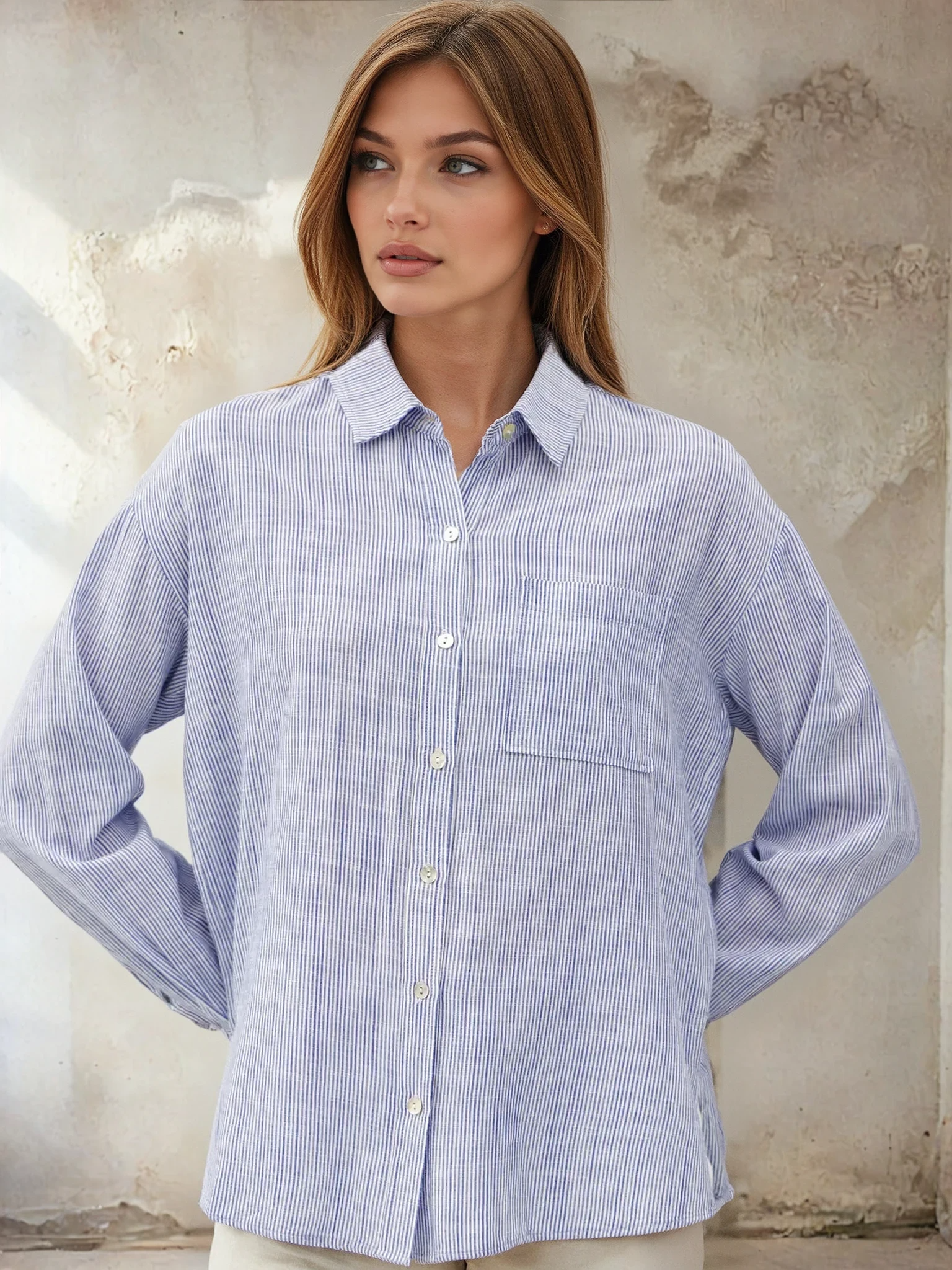 Woman wearing a blue striped shirt against a textured wall background