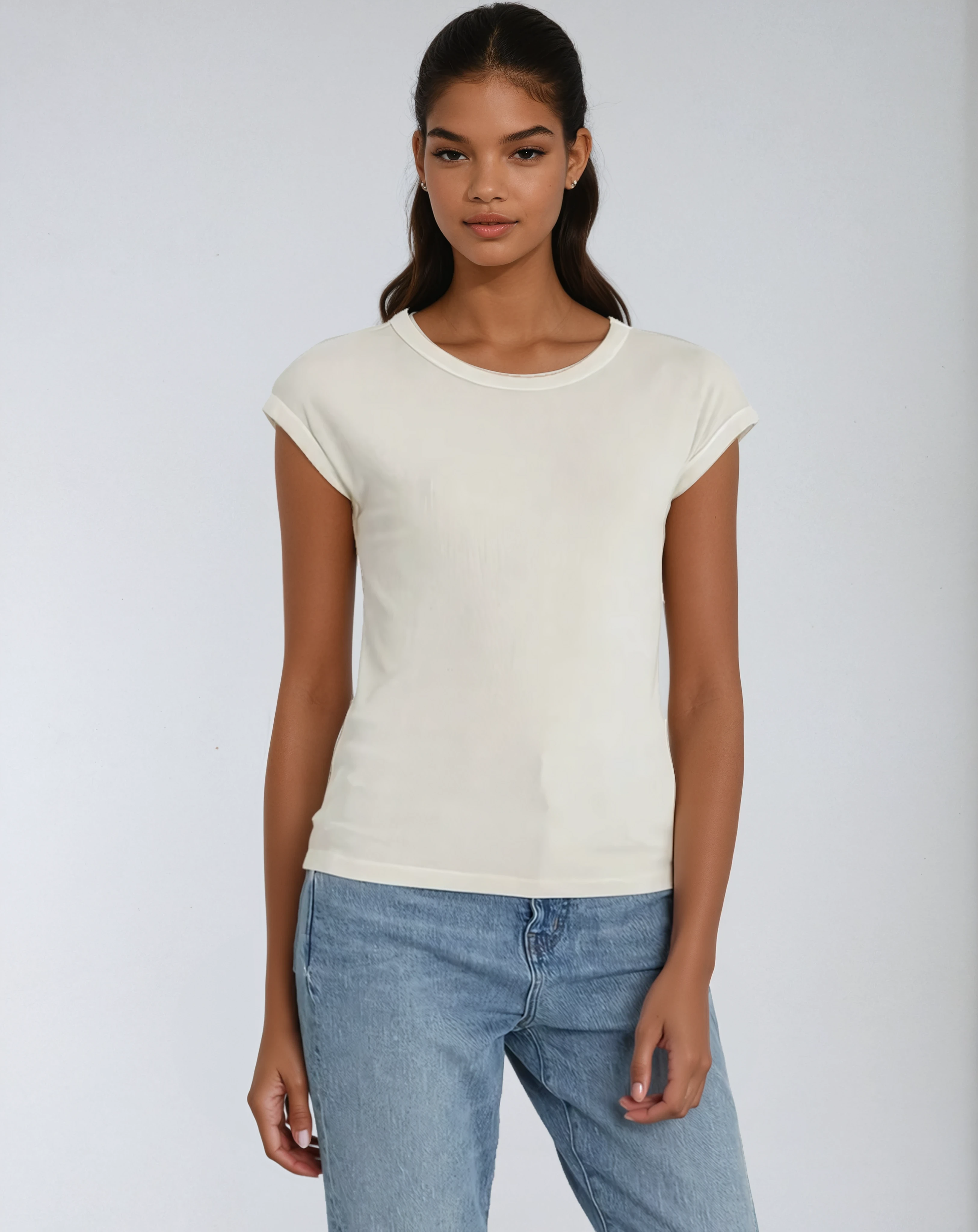 Woman wearing a white t-shirt and blue jeans against a plain background