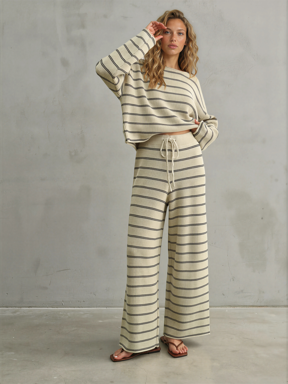 Woman wearing a striped outfit against a gray concrete wall.