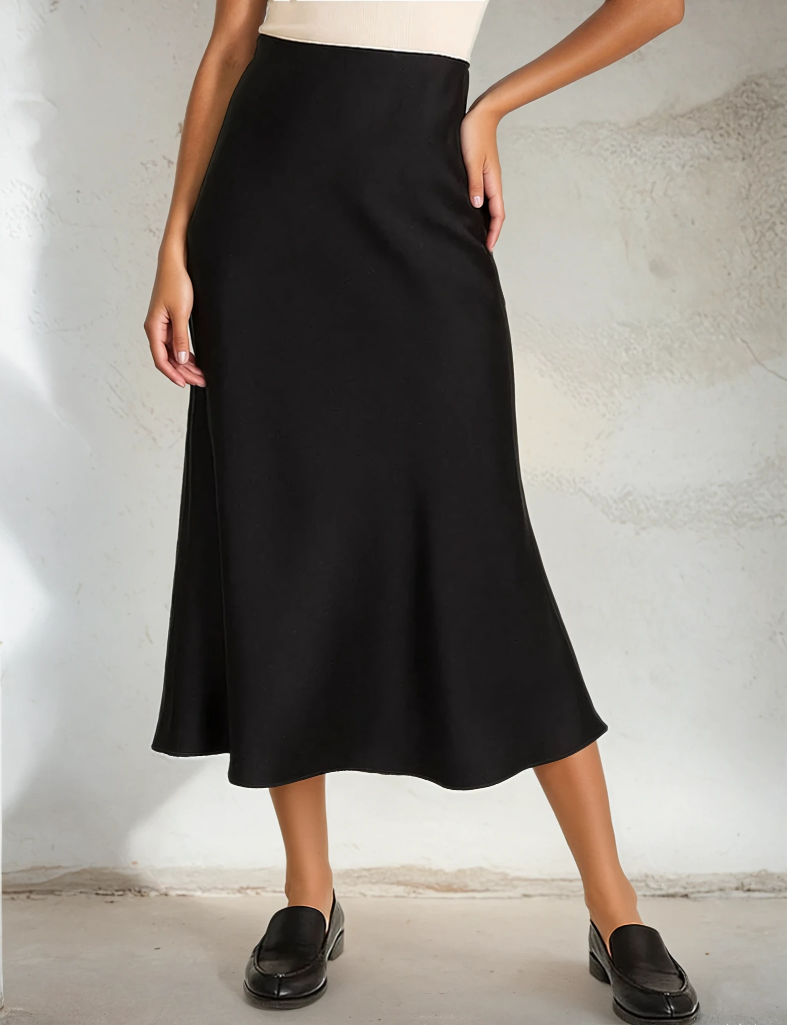 Person wearing a black skirt against a neutral background