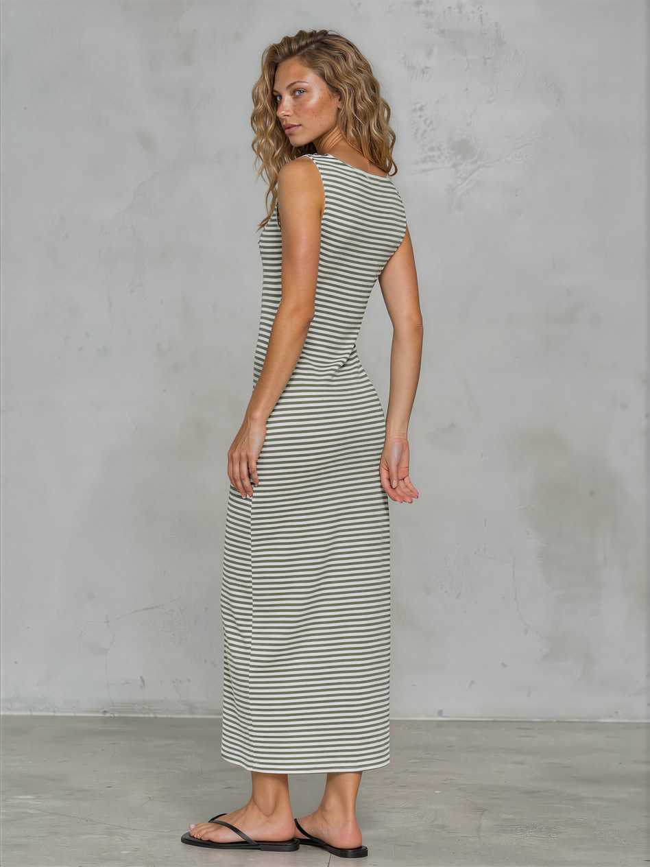 Woman wearing a striped dress against a gray concrete wall.