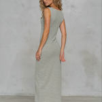 Woman wearing a striped dress against a gray concrete wall.
