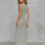 Woman wearing a striped dress against a gray concrete wall.