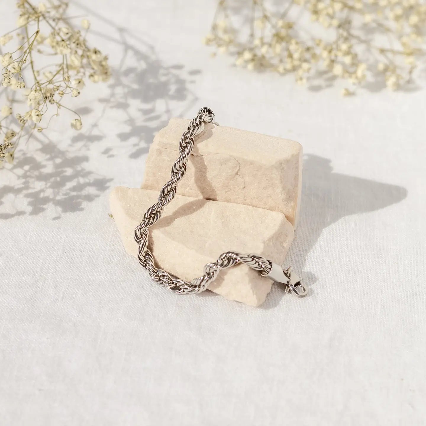 Silver chain bracelet on a textured beige surface with light background