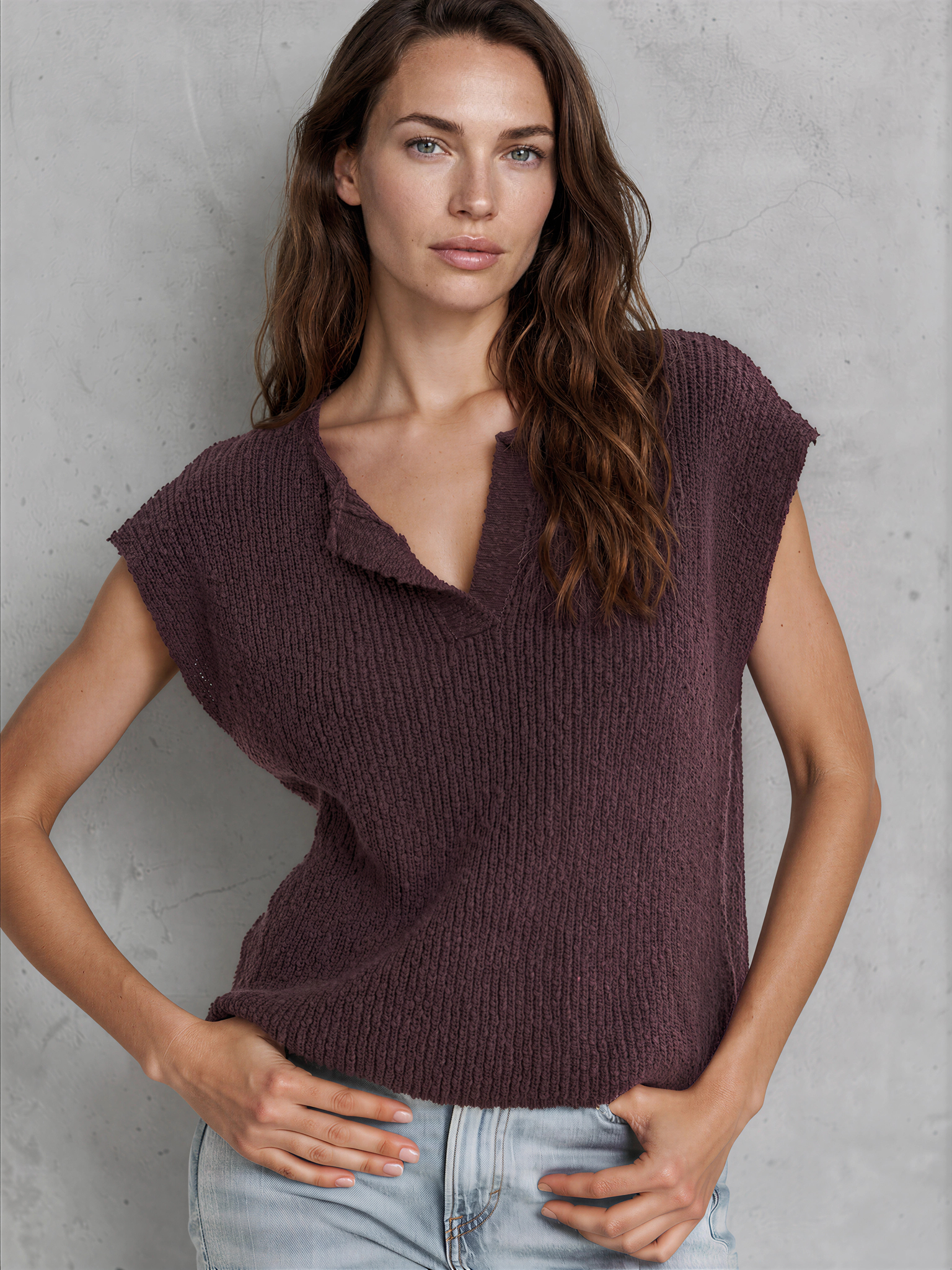 Woman wearing a brown knitted top against a gray background