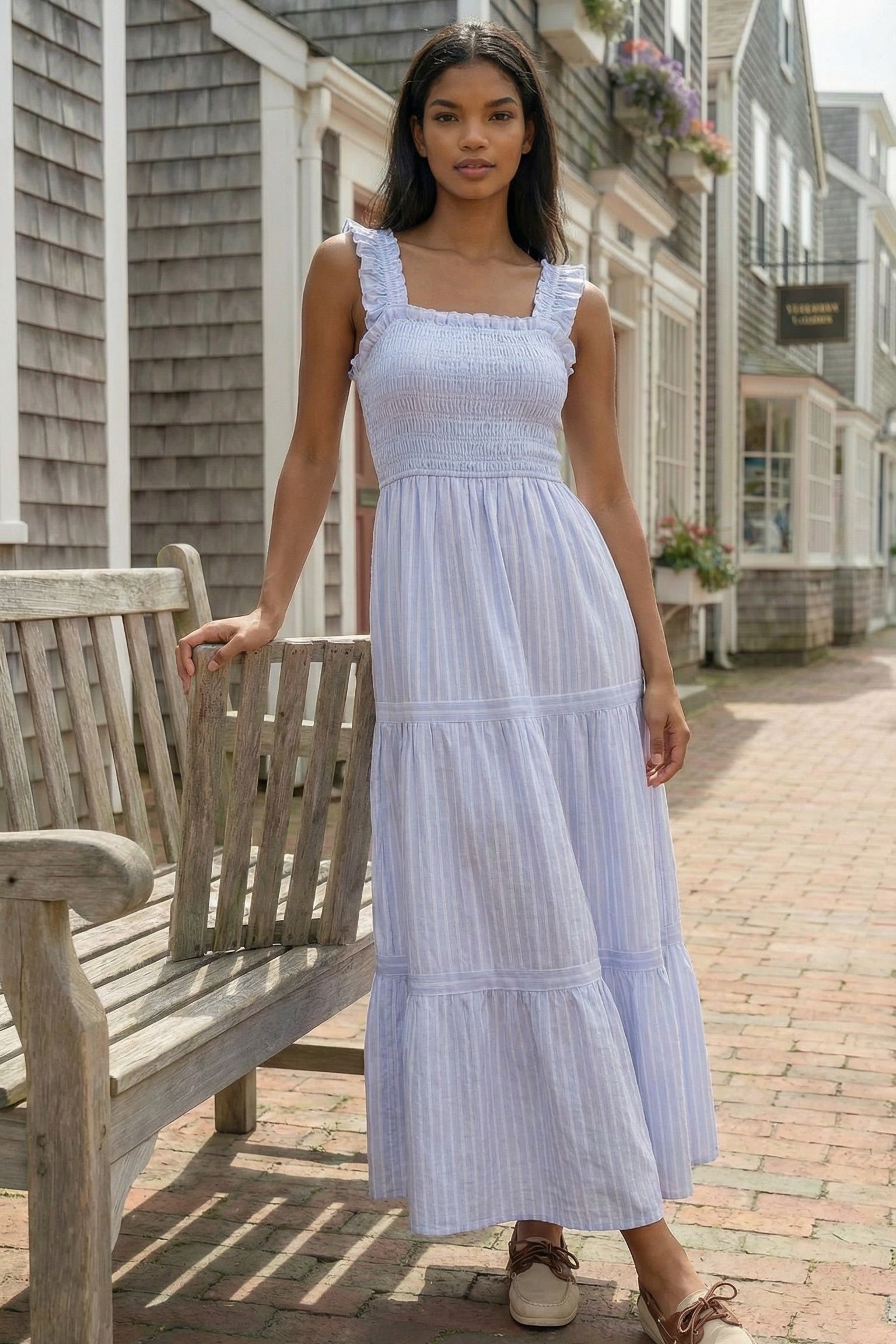 Woman in a white dress standing on a street with wooden benches and houses in the background