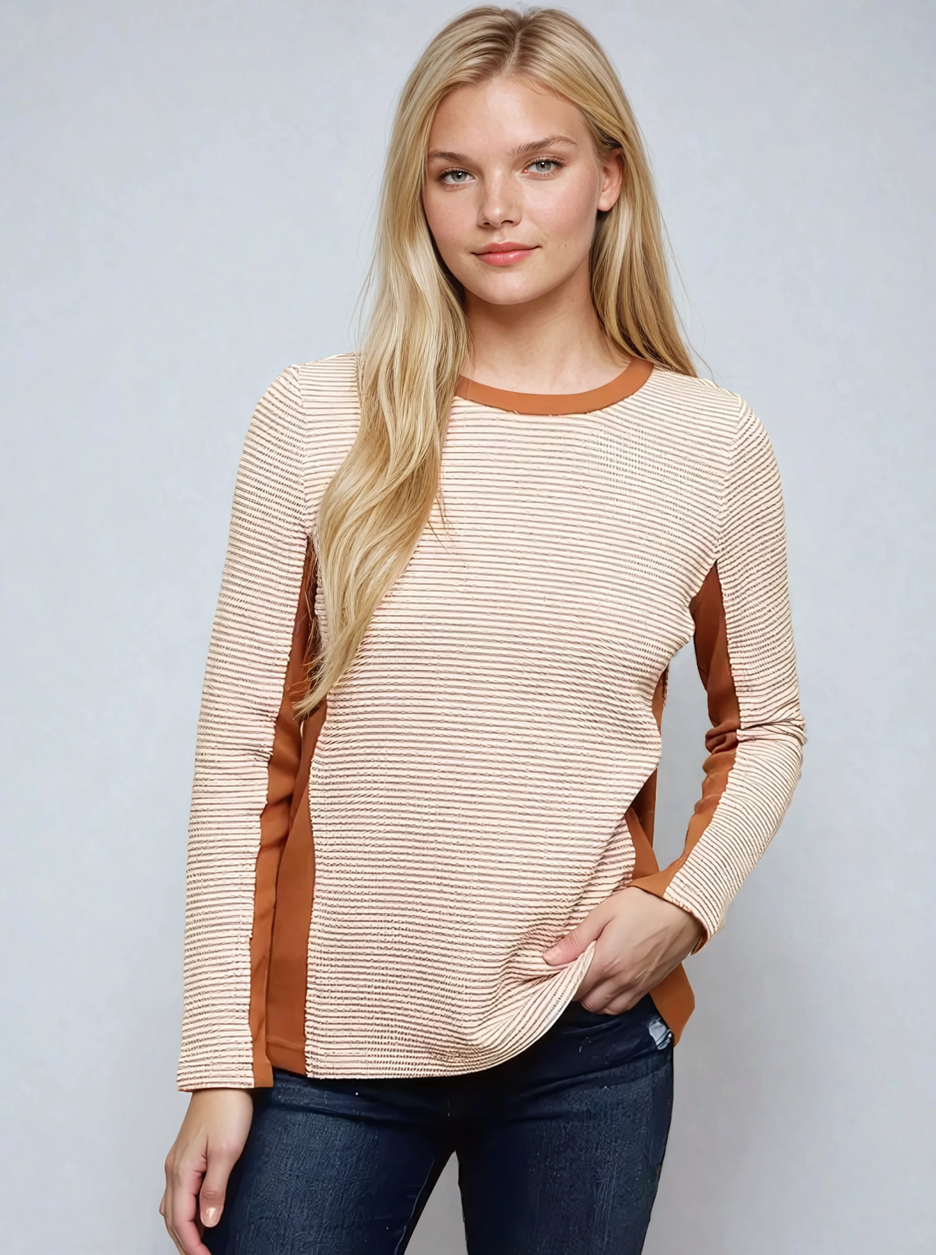 Woman wearing a beige and brown striped sweater against a plain background