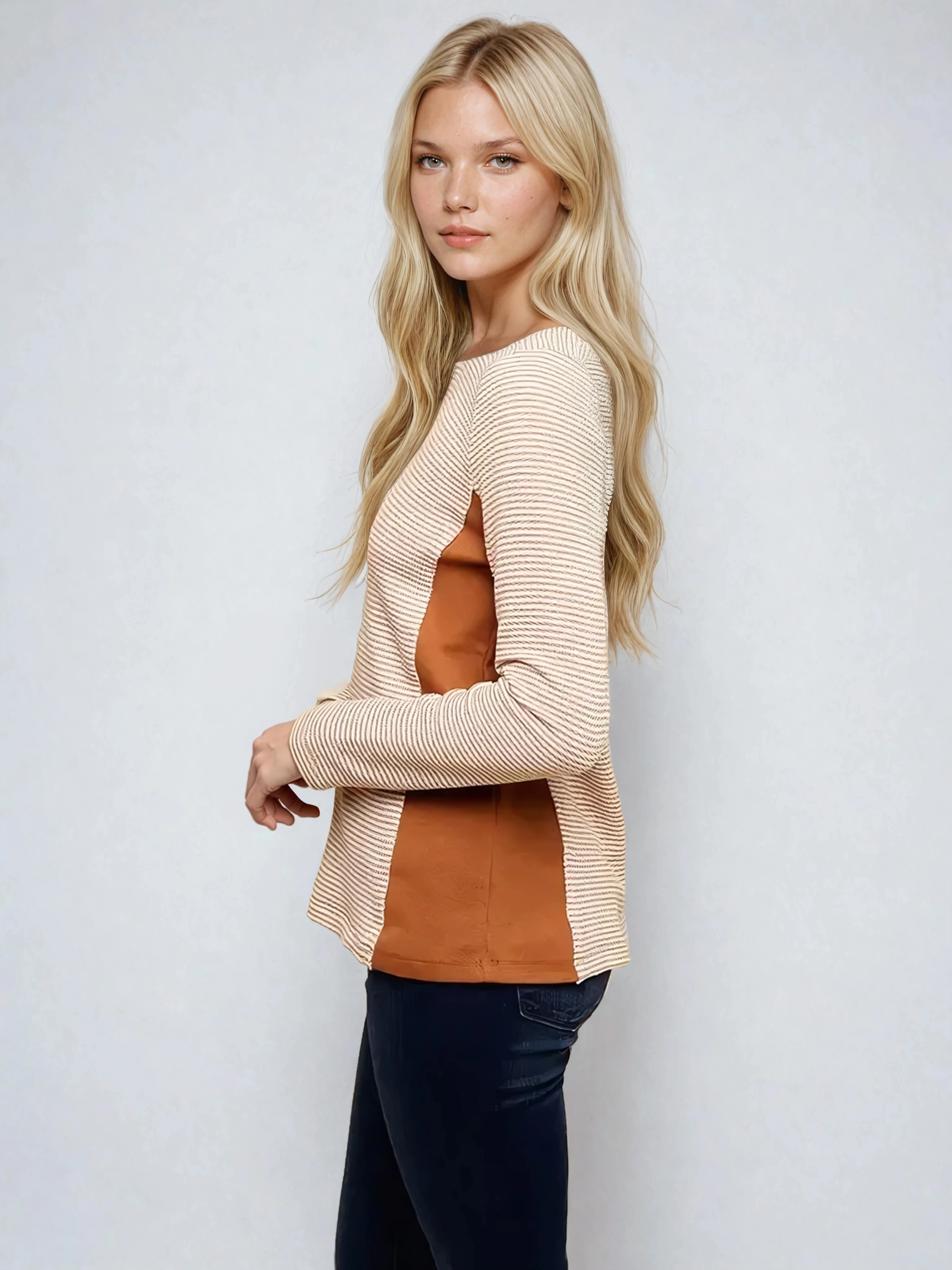 Woman wearing a beige cardigan over a brown top with black pants on a white background
