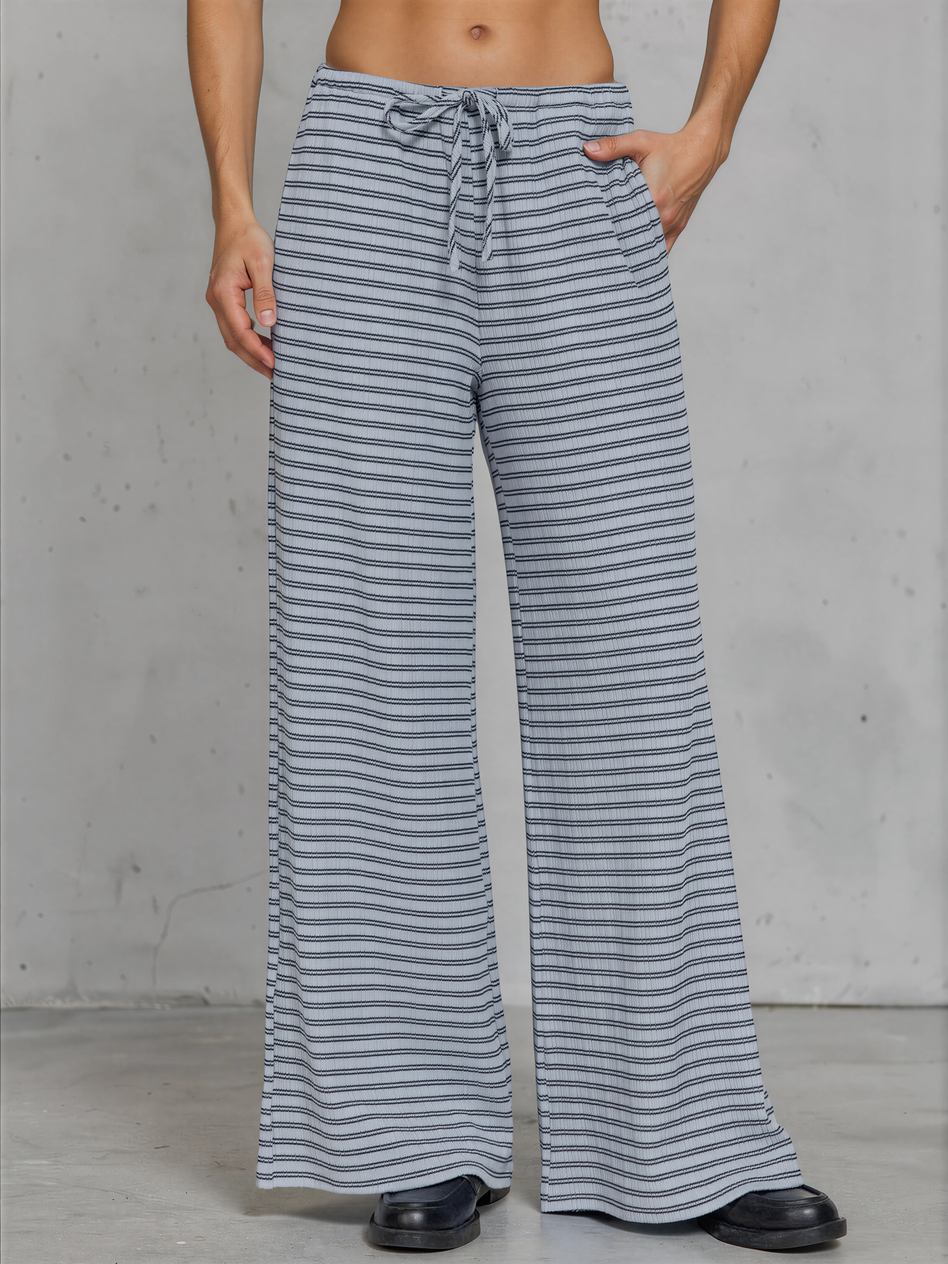 Person wearing blue and white striped wide-leg pants against a gray background