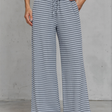 Person wearing blue and white striped wide-leg pants against a gray background