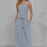 Woman wearing a blue and white striped jumpsuit against a gray background