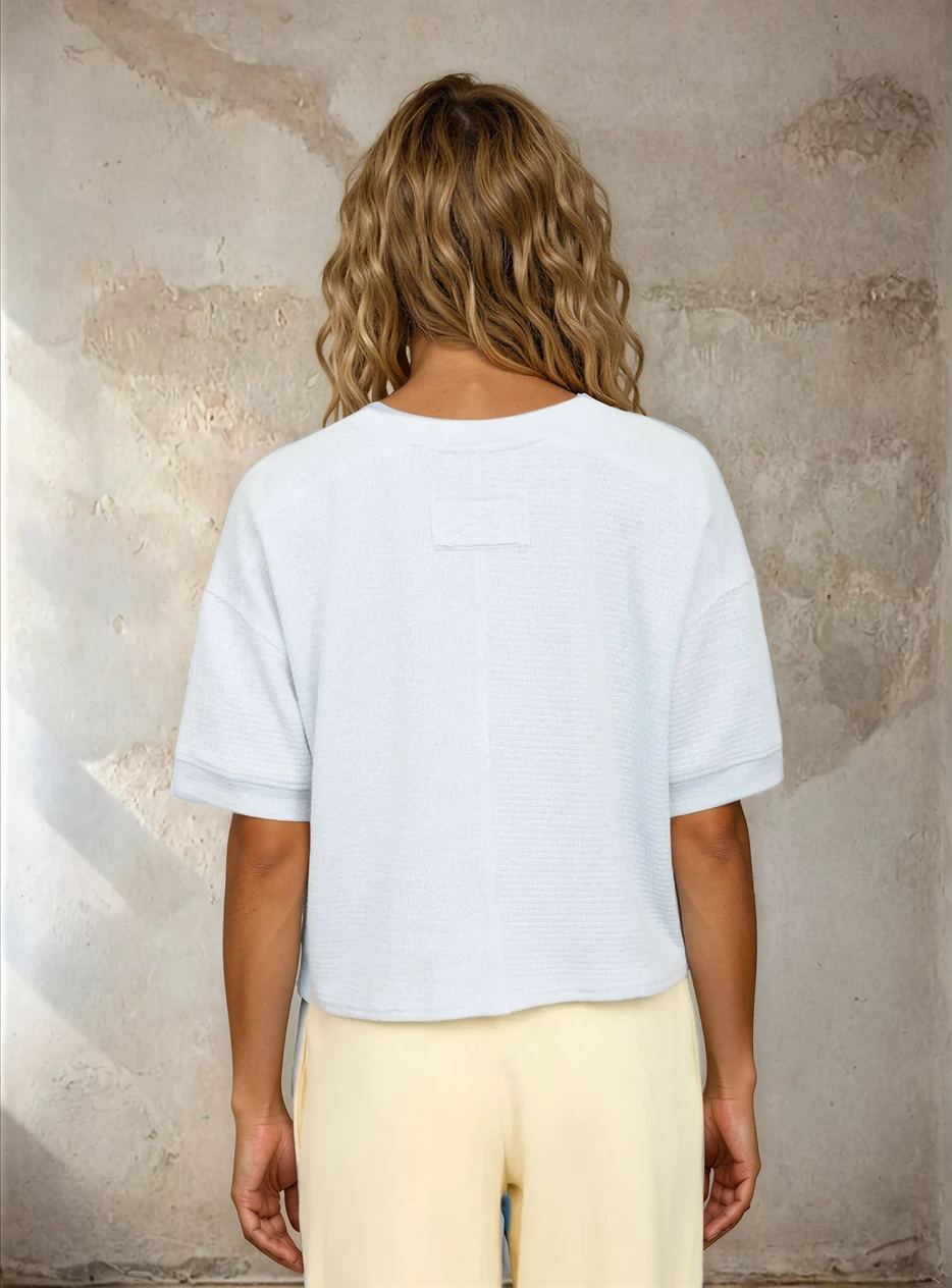 Person wearing a plain white t-shirt against a textured beige wall