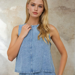 Woman wearing a light blue denim dress against a textured wall.