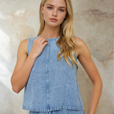 Woman wearing a light blue denim dress against a textured wall.