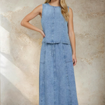 Woman wearing a denim dress against a textured wall.