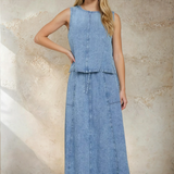 Woman wearing a denim dress against a textured wall.