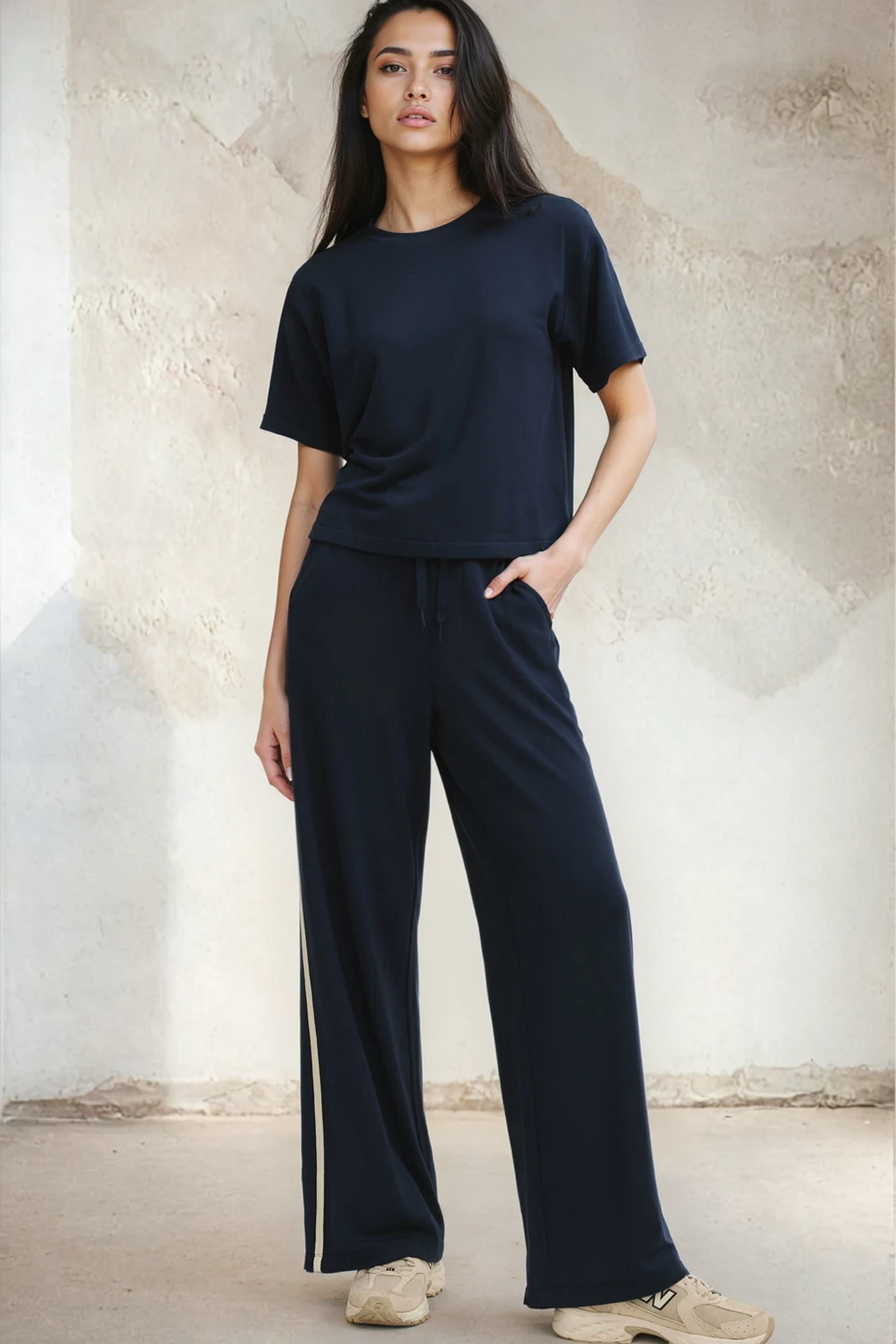Woman wearing a navy blue outfit with wide-leg pants against a neutral background