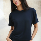 Woman wearing a black t-shirt and dark pants against a neutral background