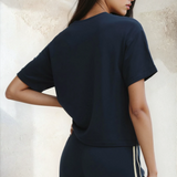 Woman wearing a navy blue outfit with a plain background