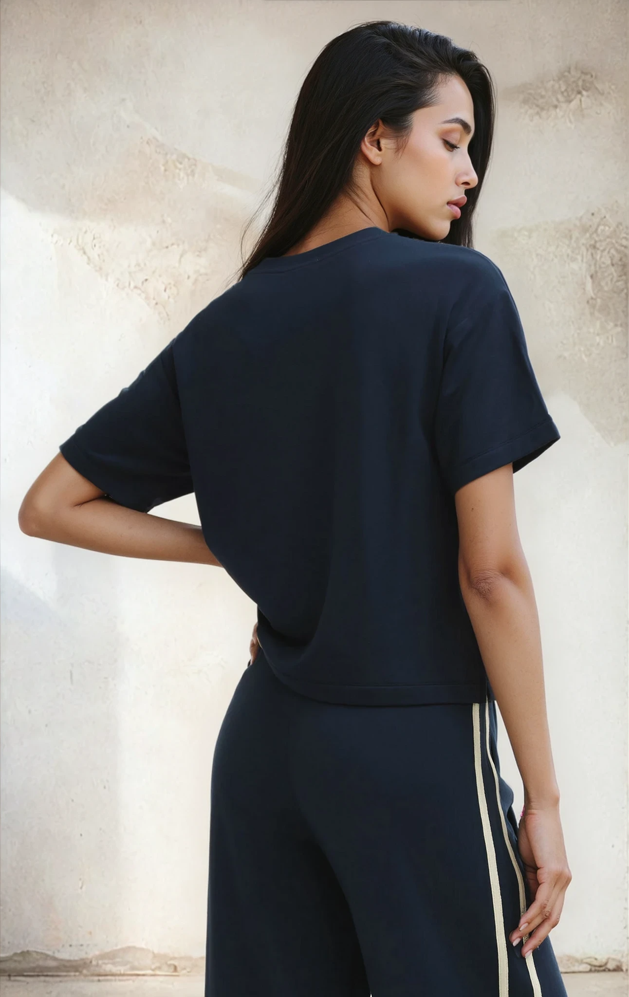 Woman wearing a navy blue outfit with a plain background