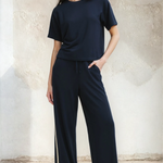 Woman wearing a navy blue outfit with wide-leg pants against a neutral background