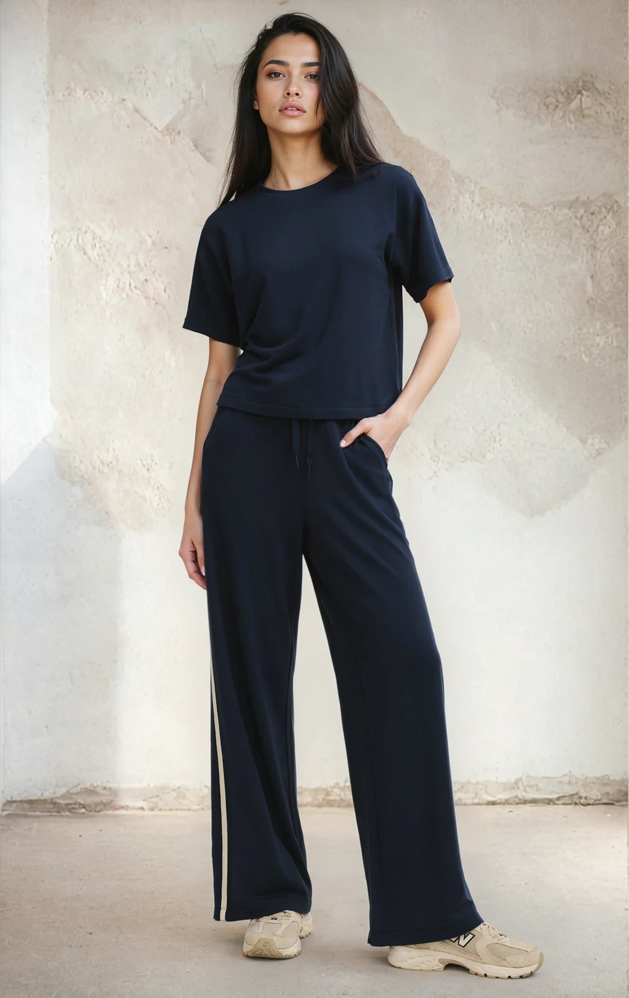 Woman wearing a navy blue outfit with wide-leg pants against a neutral background